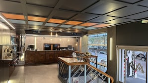 A modern interior with a bar area, wooden cabinets, and a view of the street outside.