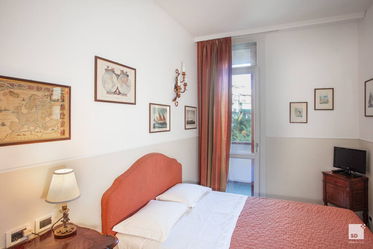 A hotel room with a bed, a TV, a lamp, and a map on the wall.