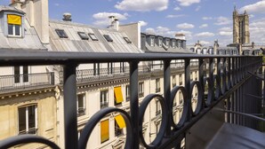 A row of historic buildings with balconies and a prominent tower in the background. - Hôtel Elixir (Paris)