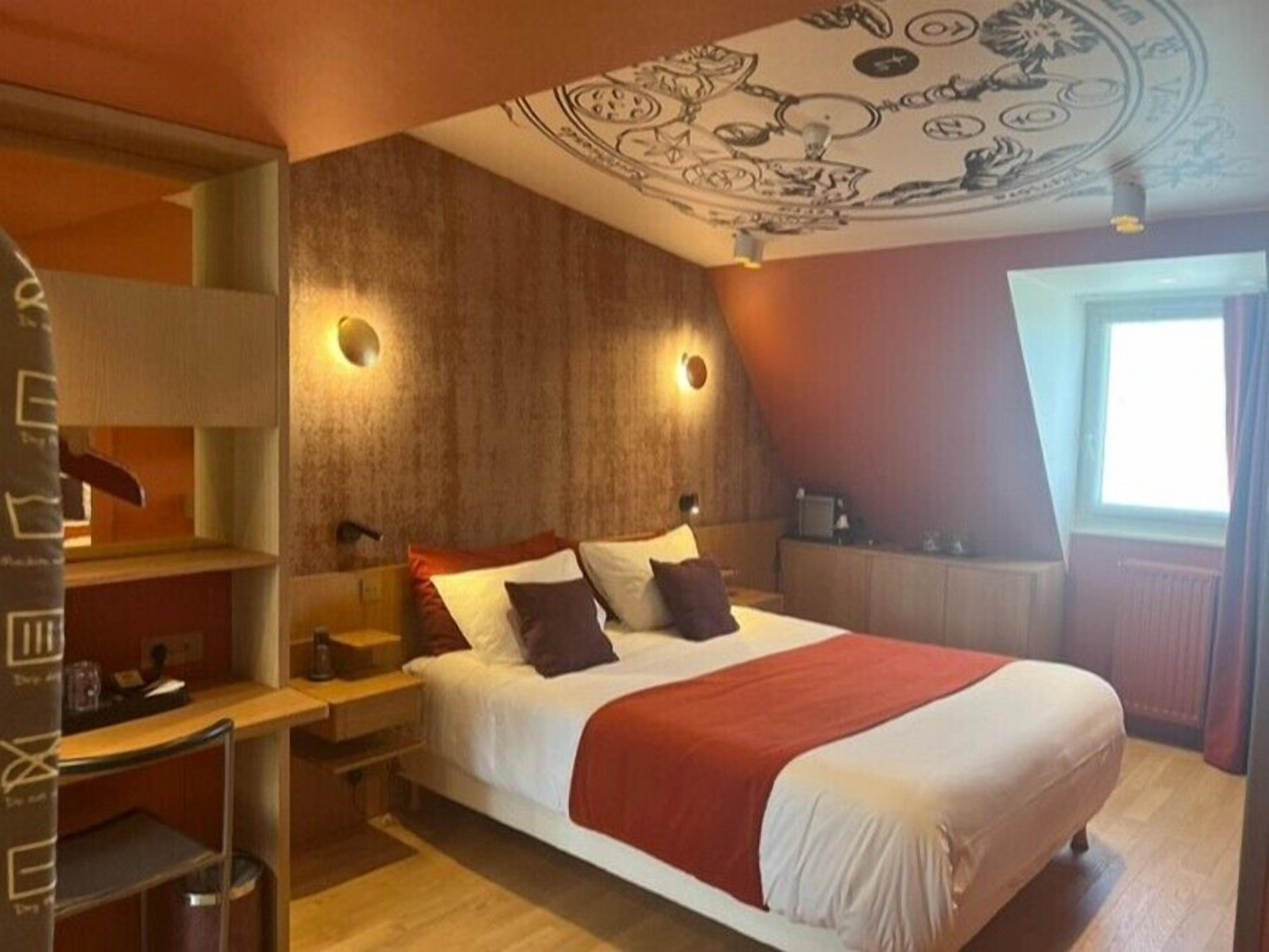 A bedroom with a large bed, wooden headboard, and a ceiling mural.