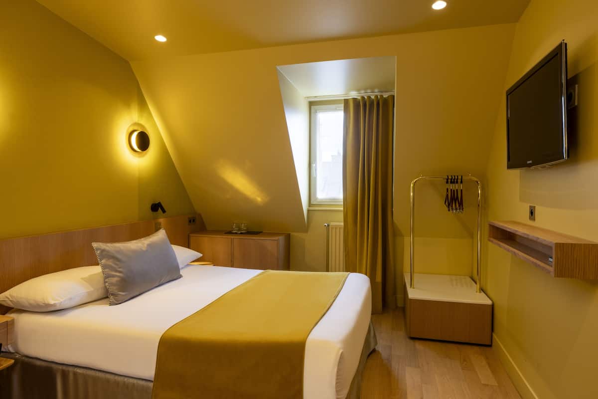 Ein Hotelzimmer mit Bett, Fernseher, Dusche und einem Fenster mit Vorhängen.