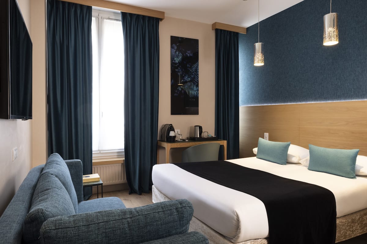 Ein Hotelzimmer mit Bett, Schreibtisch, Stuhl und einer Sitzecke.