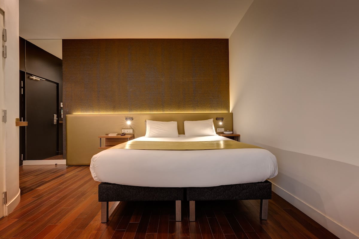 Ein modernes Hotelzimmer mit einem großen Bett, Nachttischen und Holzboden.
