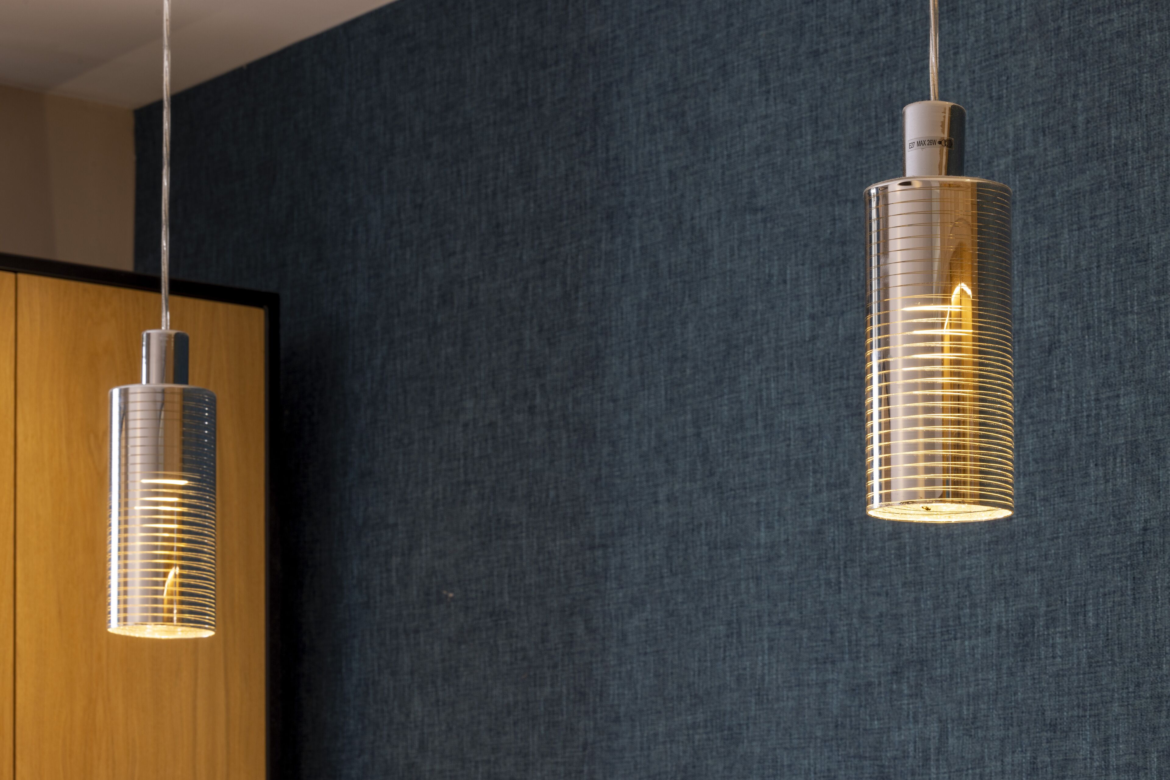 Two pendant lights with a metallic finish and a visible filament bulb, hanging from a ceiling.