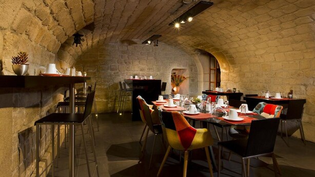A dining area with brick walls, tables set with plates, cups, and cutlery. - Hôtel Elixir (Paris)