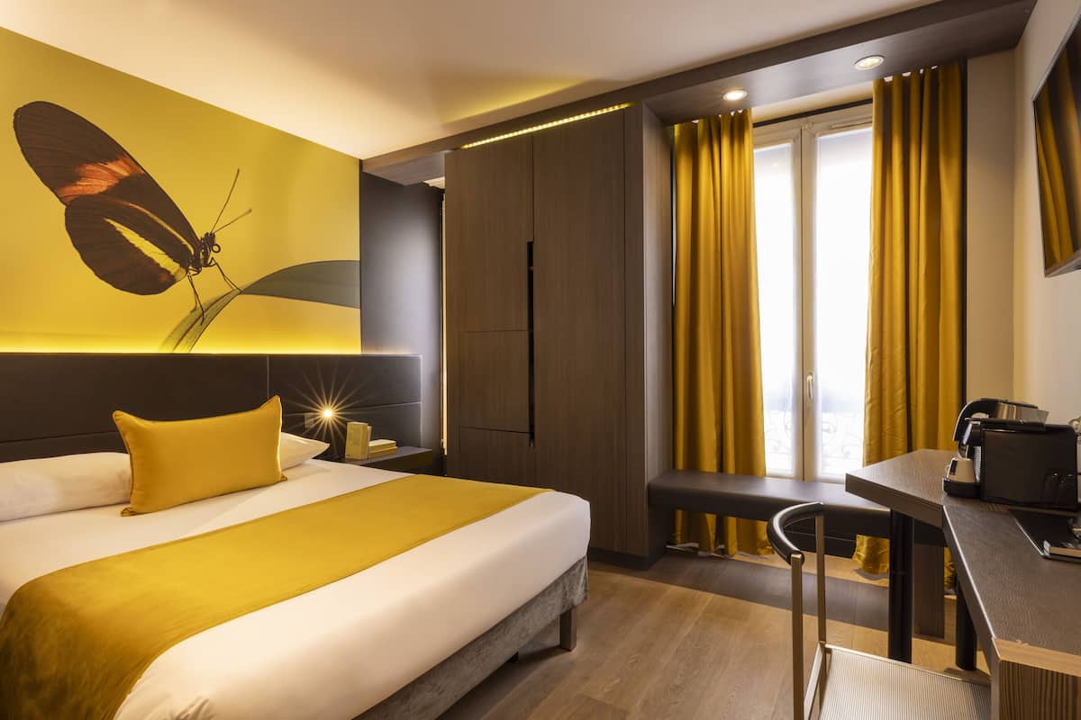 Ein modernes Hotelzimmer mit Bett, Schreibtisch, einer Bank und einem großen Wandbild mit Schmetterlingen.