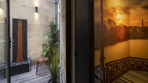 A hotel entrance with a stone wall, a modern sculpture, and a potted plant. - Hôtel Elixir (Paris)
