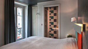 Habitación de hotel con cama, puerta de diseño cuadriculado, cortinas en la ventana y una lámpara de pared.