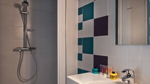 Un baño con ducha, lavamanos y espejo.