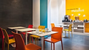 Un café luminoso y colorido con mesas y sillas, una máquina de café y una barra con productos alimenticios.