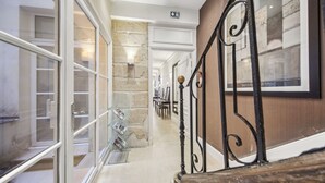 Un couloir avec une vitrine, un mur en pierre et un escalier doté d’une balustrade noire.