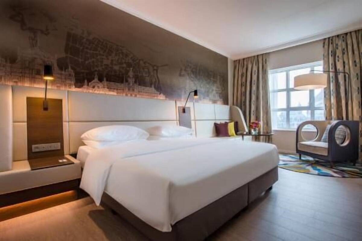 Habitación de hotel con una cama grande, un escritorio, una silla y una ventana con cortinas.