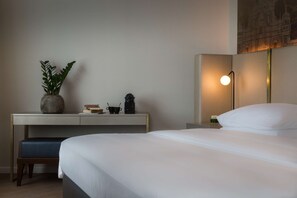 Habitaci ón de hotel con cama, escritorio con planta, cafetera y lámpara de pared.