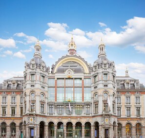 A grand, historic building with a central clock tower, large arched windows, and ornate architectural details. - Radisson Blu Hotel, Antwerp City Centre (Antwerp)