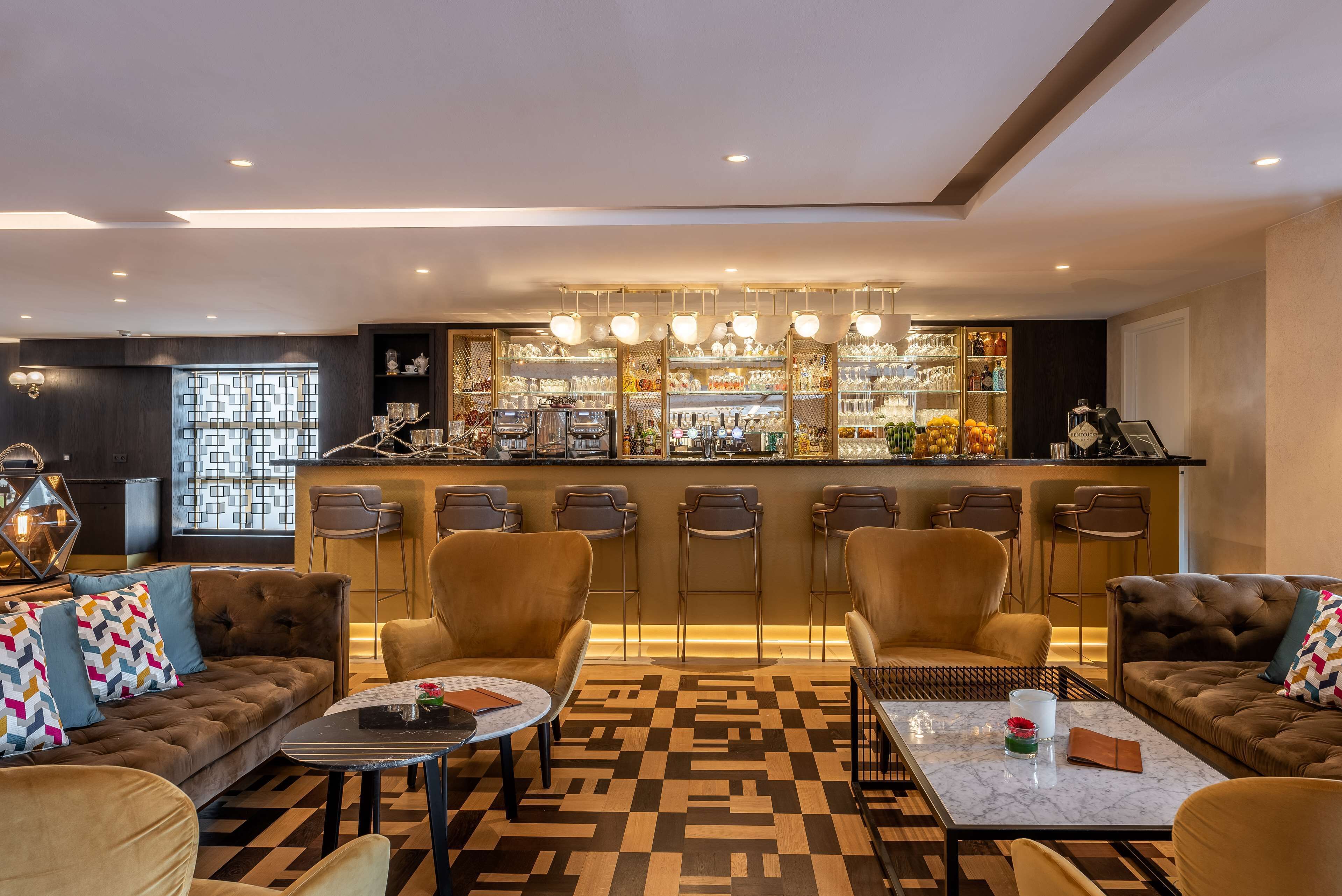 A modern bar area with a bar counter, seating, and a patterned floor.