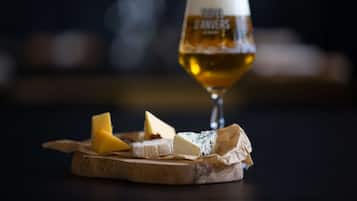 Una tabla de madera con varios quesos y una jarra de cerveza.