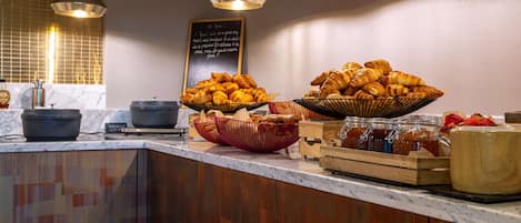 A breakfast buffet with croissants, jams, and other pastries.