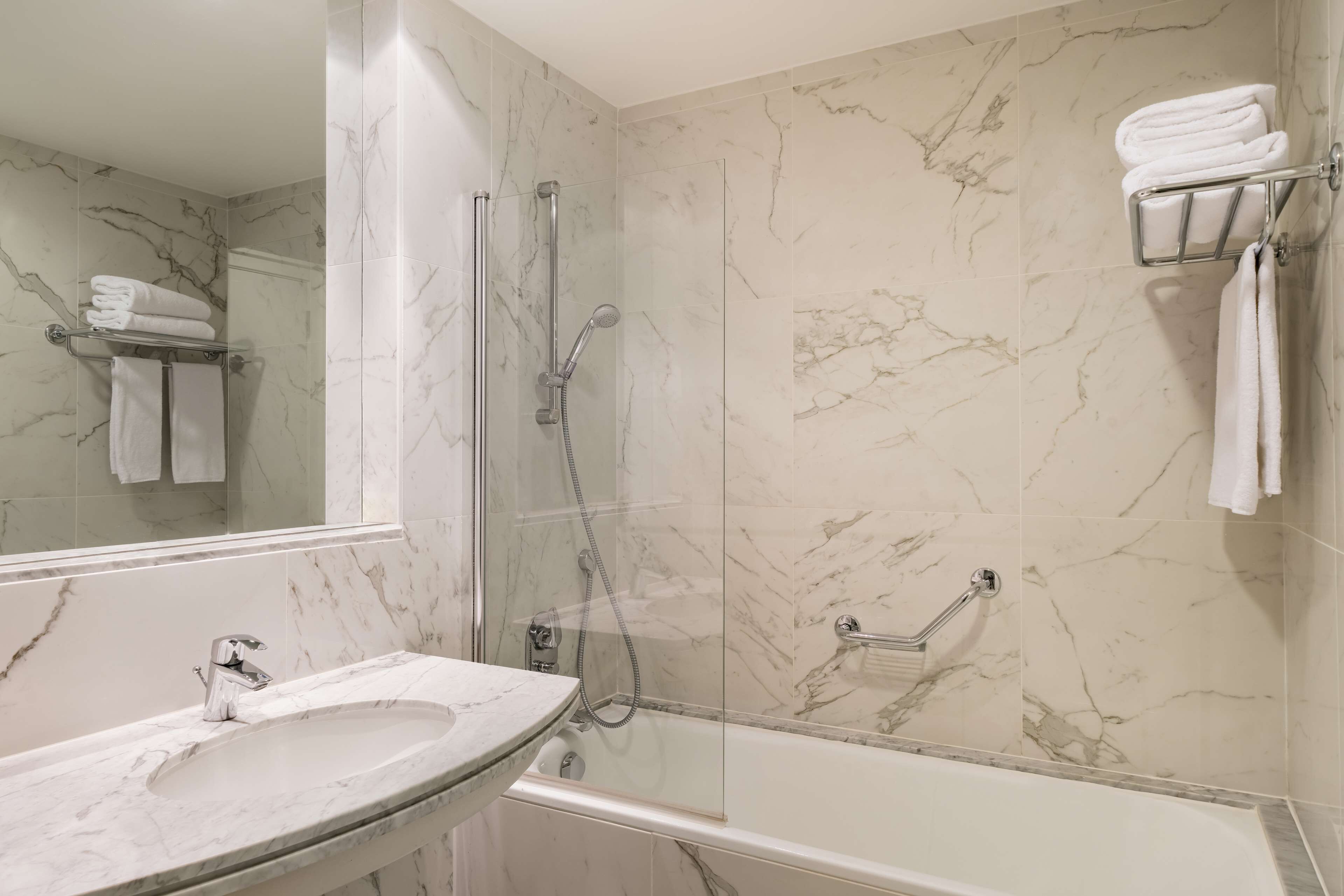 A bathroom with a marble sink, a glass-enclosed shower, and a bathtub.