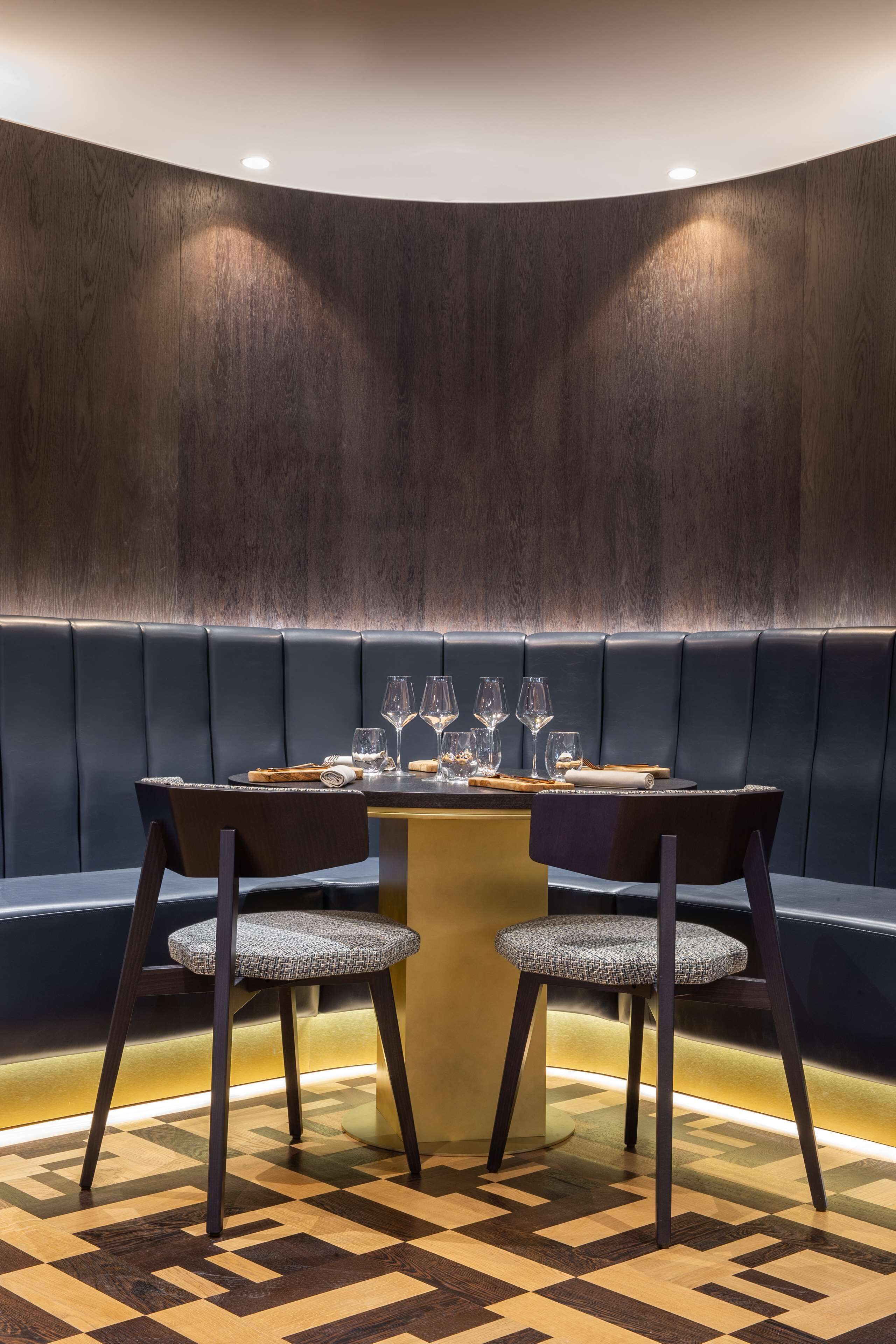 A dining area with a round table, two chairs, and a bench.