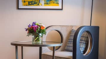 Een moderne kamer met een ronde tafel, een stoel met een bijzondere ronde rugleuning, een vloerlamp en twee ingelijste kunstwerken aan de muur.
