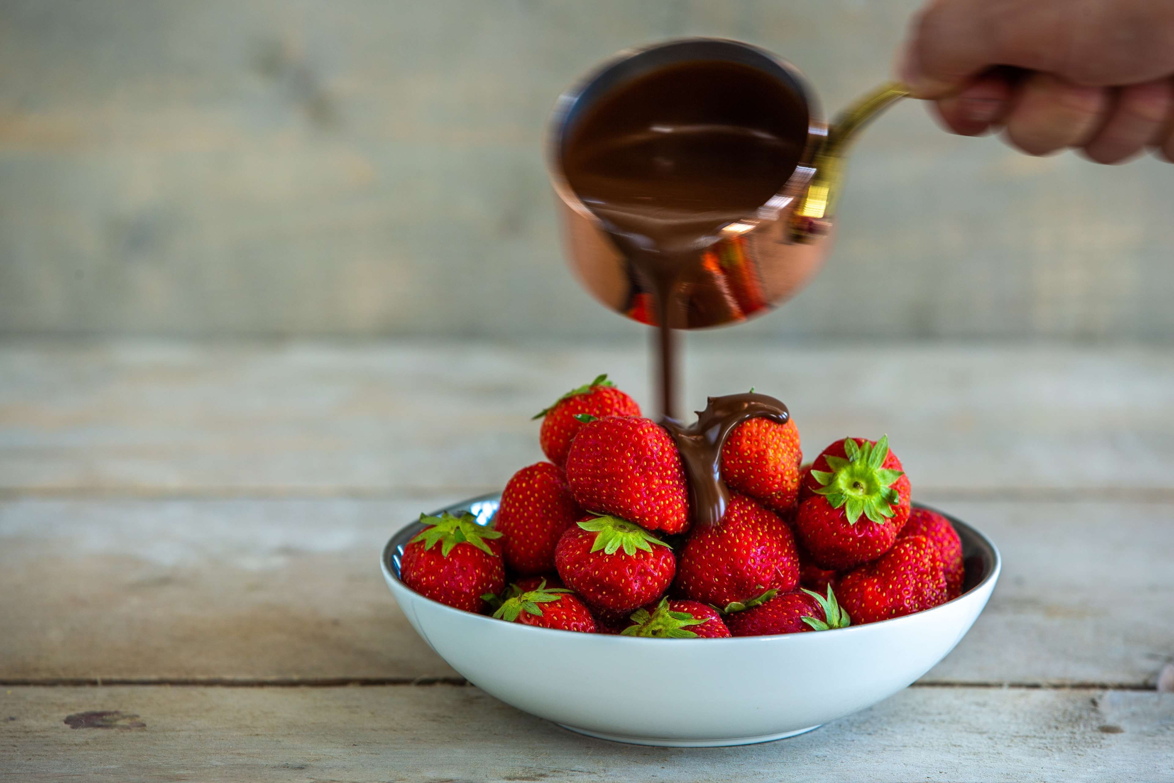 Un bol de fraises sur lesquelles on verse du sirop.