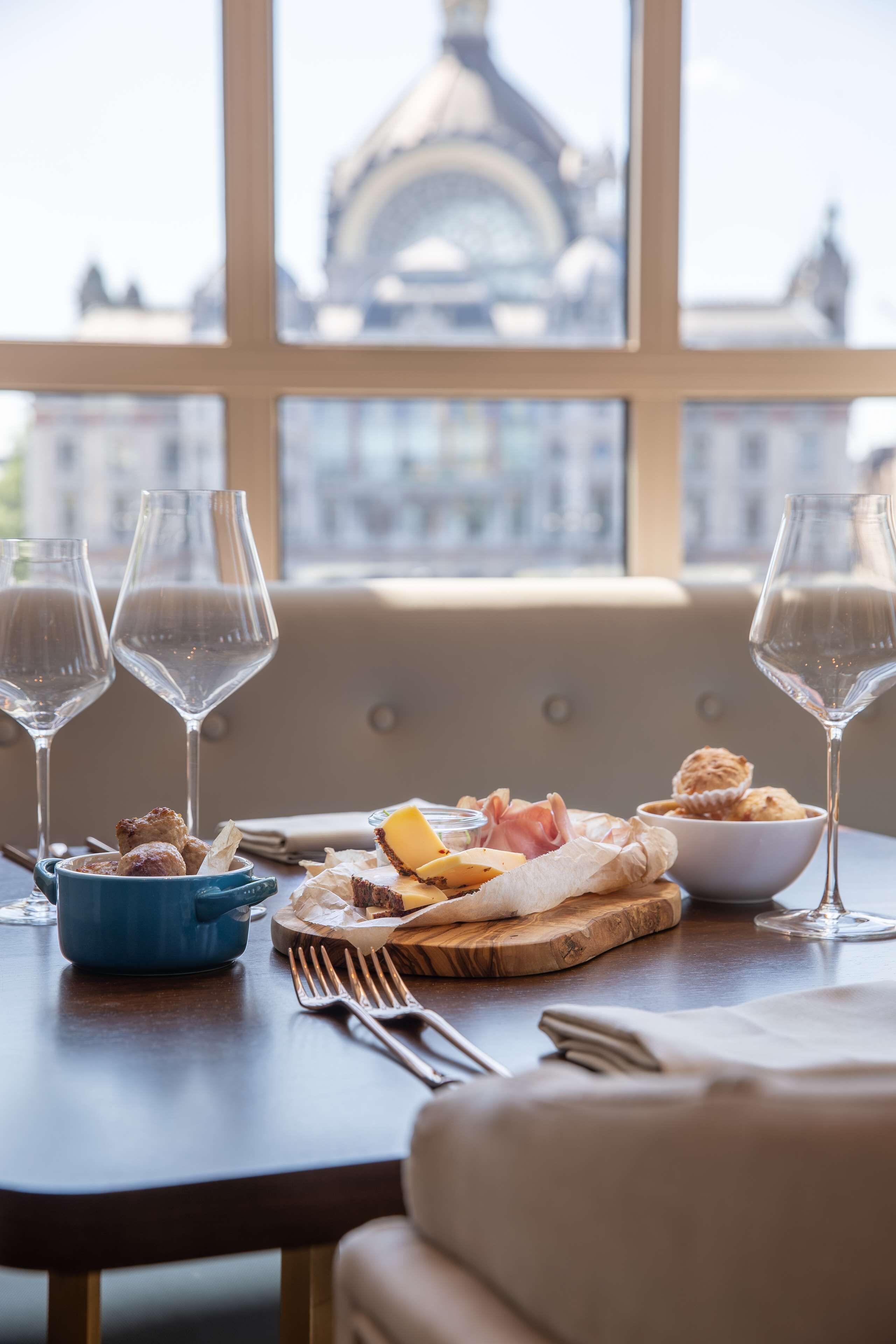 Een eettafel met wijnglazen, een schaal gebak en een bord eten.