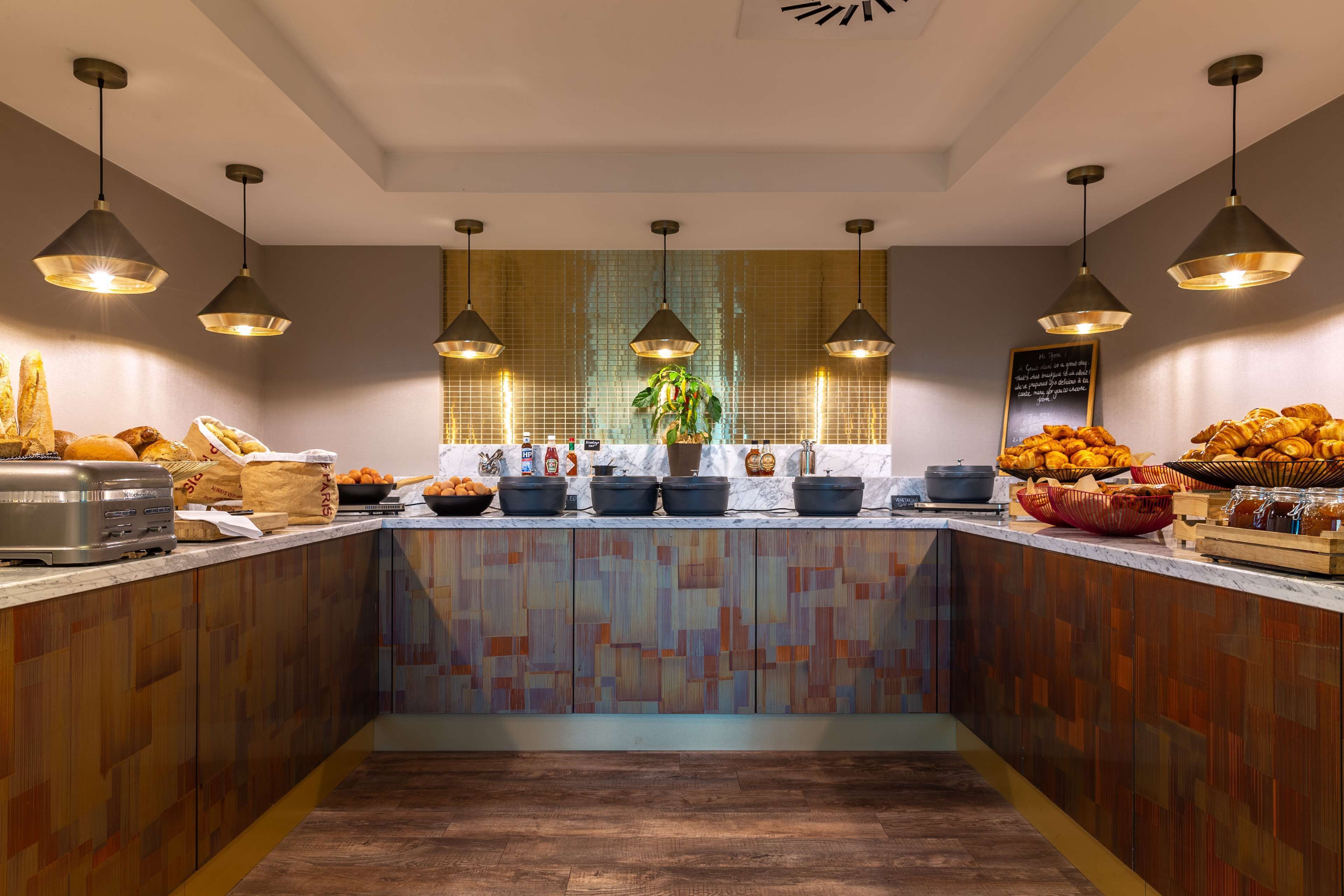 Una cocina moderna con armarios de madera, salpicadero de azulejos e iluminación colgante.
