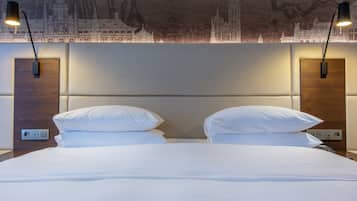 A hotel room with a large bed, two bedside lamps, and a wall mural.