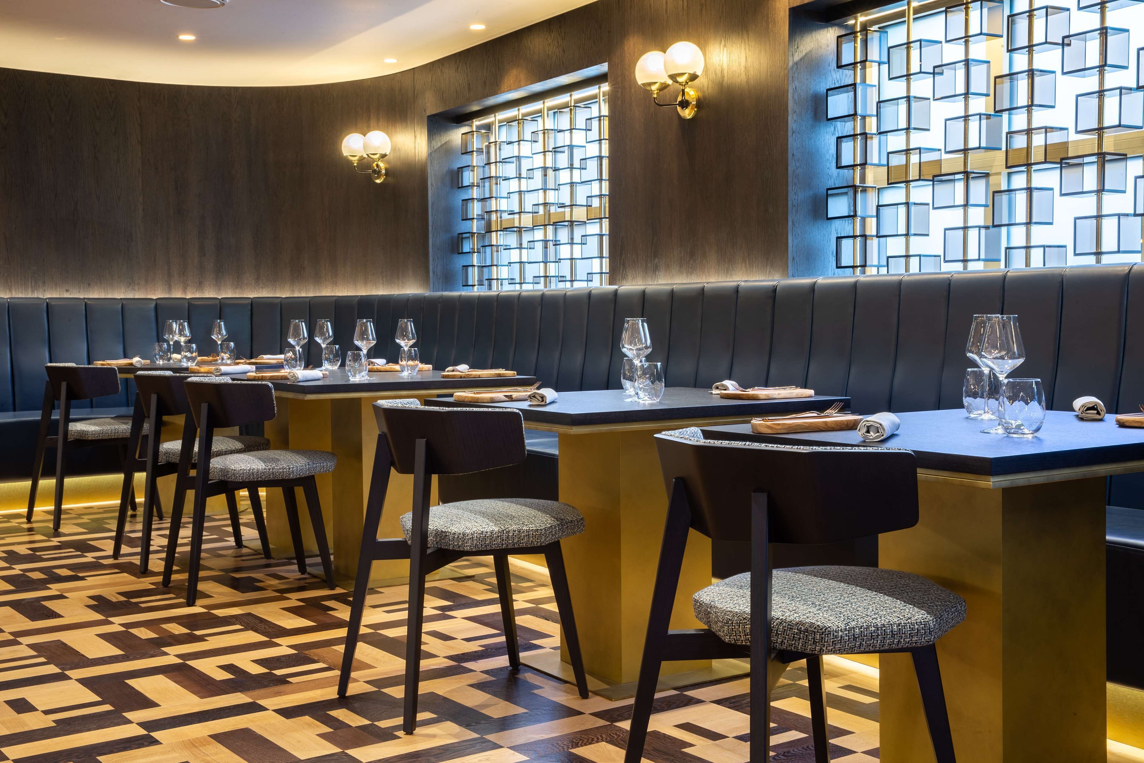 Un restaurante con suelo a cuadros, paredes oscuras y una isla central con asientos.