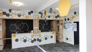 A reception area with a modern design, featuring hexagonal patterns on the walls and a reception desk. - ibis Styles Poitiers Nord (Poitiers)