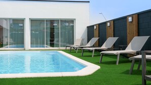 A modern outdoor pool area with a rectangular pool, surrounded by artificial grass, and equipped with several lounge chairs. - ibis Styles Poitiers Nord (Poitiers)