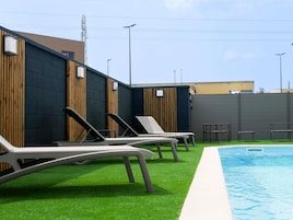 Una piscina al aire libre de temporada, sombrillas