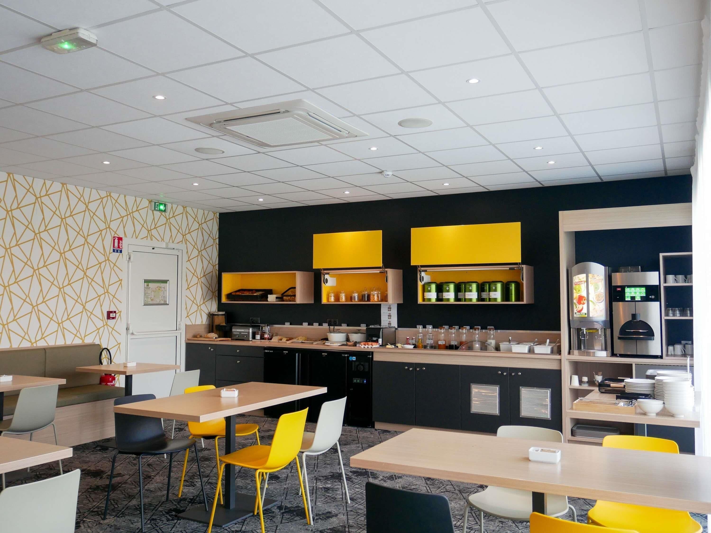 A modern kitchen area with built-in appliances, a coffee machine, and a seating area with tables and chairs.