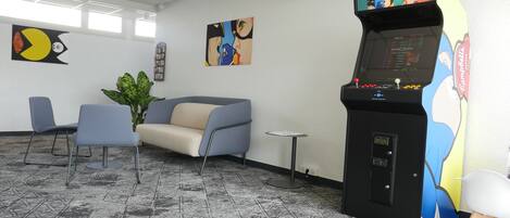 Una habitación con un sofá, sillas, una mesita y una máquina de juegos.