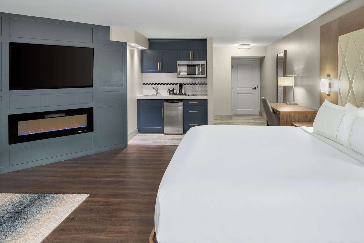 Een moderne hotelkamer met een groot bed, een ingebouwde televisie, een kitchenette en een zithoek.