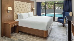 Une chambre d’hôtel avec un grand lit, un bureau, une chaise et une vue sur une piscine.