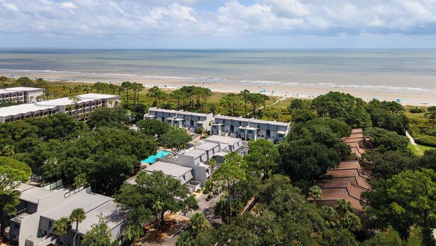 Un complexe hôtelier comprenant plusieurs bâtiments, une piscine et offrant une vue sur la plage.