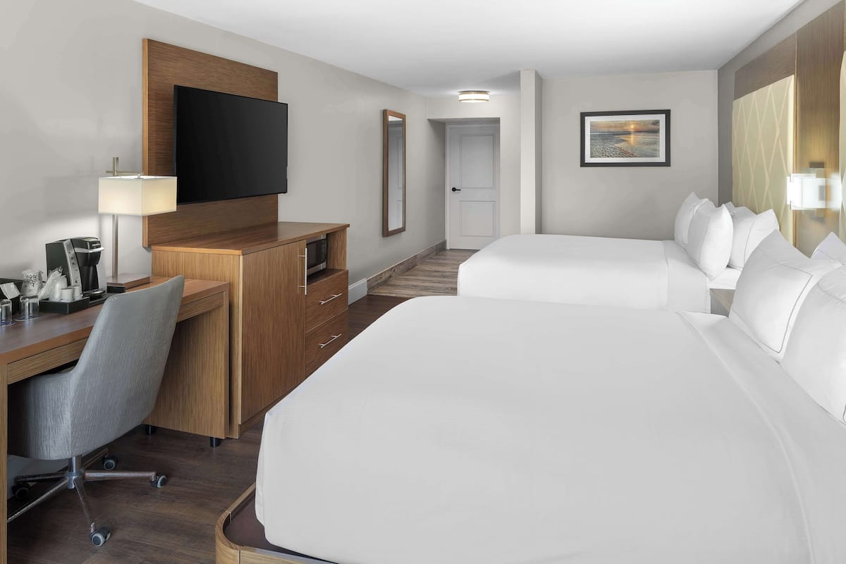 Hotelkamer met een groot bed, een bureau met een stoel, een televisie en een klein werkgedeelte met een lamp.