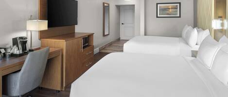 Une chambre d’hôtel avec un grand lit, un bureau avec une chaise, une télévision et un petit espace bureau équipé d’une lampe.