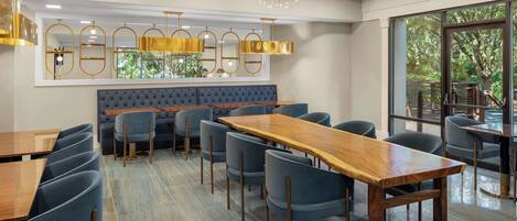 A modern dining area with a long wooden table, blue upholstered chairs, and a tufted bench.