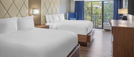 A hotel room with two beds, a desk, and a balcony with a view.
