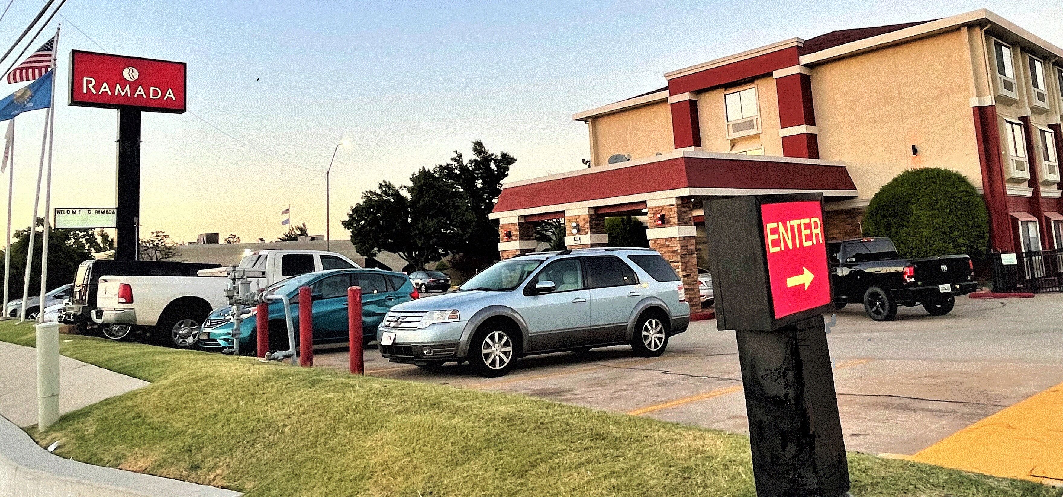 A parking lot with several cars, a sign for Ramada, and a building with an 'ENTER' sign.
