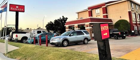A parking lot with several cars, a sign for Ramada, and a building with an 'ENTER' sign.