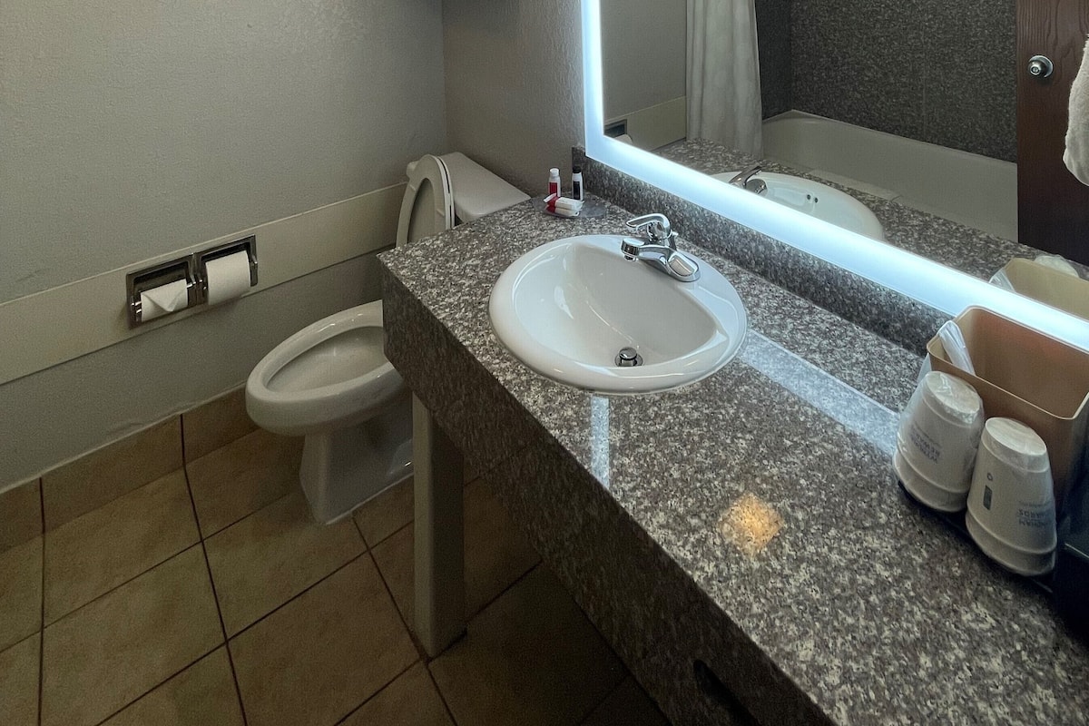 A bathroom with a white sink, a mirror, a toilet, and a towel rack.