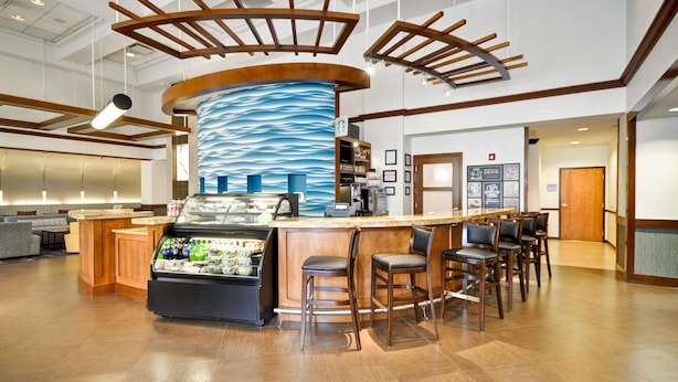 A modern bar area with a curved counter, bar stools, and a display case with beverages.