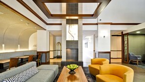 A modern lobby with a seating area, a fireplace, and a view of the hallway.