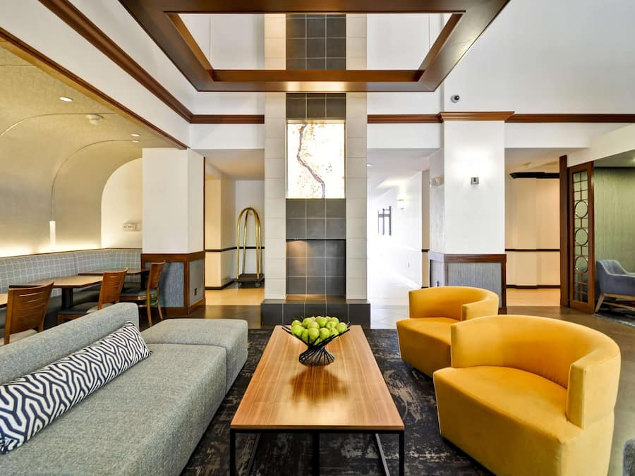 A modern lobby with a seating area, a fireplace, and a view of the hallway.