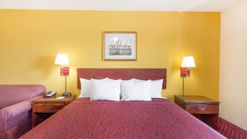 A hotel room with a large bed, two bedside tables, a nightstand, a lamp, and a framed picture on the wall.