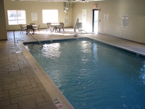 An indoor swimming pool with a tiled floor, a lifeguard chair, and a pool lift. - Holiday Inn Express Vernon - Manchester by IHG (Vernon)