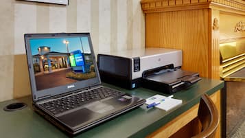Un mostrador de recepción de hotel con una computadora portátil, una impresora y un cesto de basura.